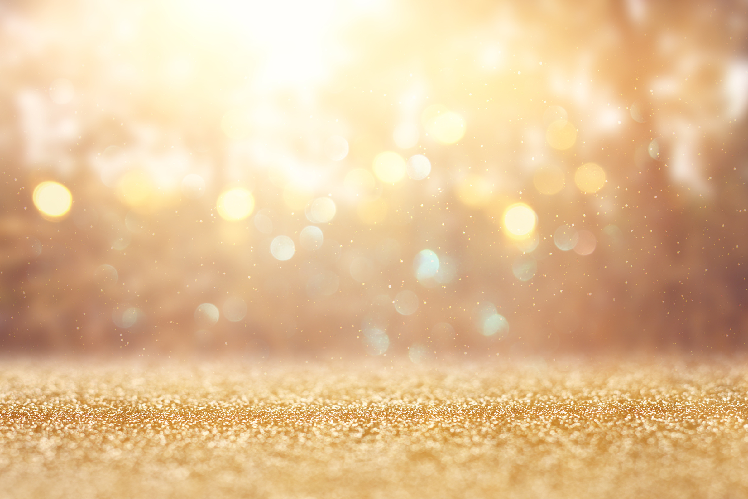 blurred abstract photo of light burst among trees and glitter golden bokeh lights.